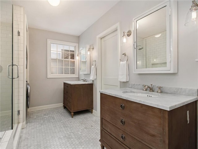 full bath with a shower stall, baseboards, two vanities, and a sink
