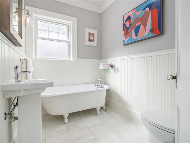 full bathroom with toilet, a wainscoted wall, ornamental molding, and a freestanding tub