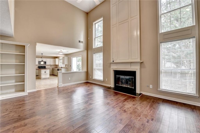 12060 Carriage Park Ln, Duluth, GA 30097 - unfurnished living room with a towering ceiling, wood finished floors, a fireplace, and baseboards