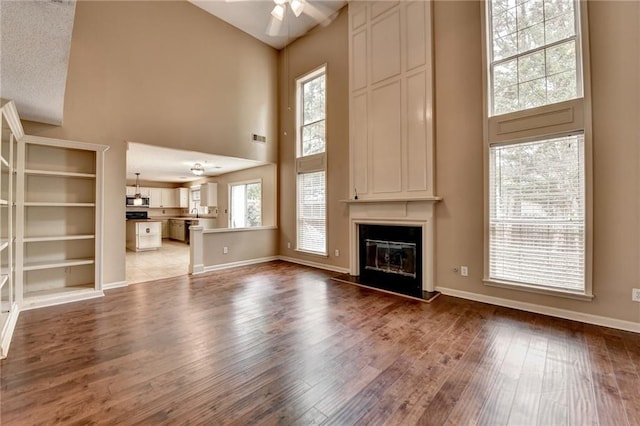 12060 Carriage Park Ln, Duluth, GA 30097 - unfurnished living room featuring high vaulted ceiling, a ceiling fan, a large fireplace, wood finished floors, and baseboards