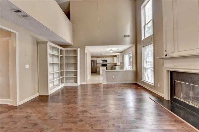 12060 Carriage Park Ln, Duluth, GA 30097 - unfurnished living room featuring wood finished floors, a fireplace, a towering ceiling, and baseboards