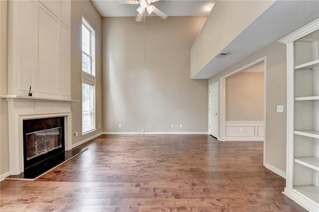 12060 Carriage Park Ln, Duluth, GA 30097 - unfurnished living room with a ceiling fan, wood finished floors, a fireplace, built in shelves, and a high ceiling