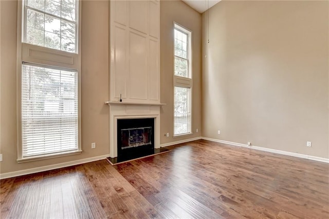 12060 Carriage Park Ln, Duluth, GA 30097 - unfurnished living room with wood finished floors, a high ceiling, baseboards, and a large fireplace