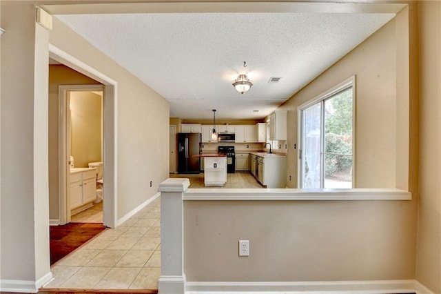 12060 Carriage Park Ln, Duluth, GA 30097 - kitchen with fridge with ice dispenser, black range, stainless steel microwave, a sink, and light tile patterned flooring