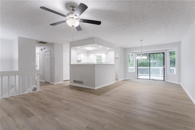 740 Stoneside Ct, Stone Mountain, GA 30083 - unfurnished living room featuring a textured ceiling, light wood-type flooring, baseboards, ceiling fan, and a chandelier