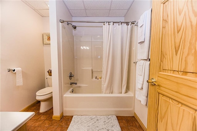 bathroom featuring shower / bath combination with curtain, a paneled ceiling, tile patterned floors, and toilet