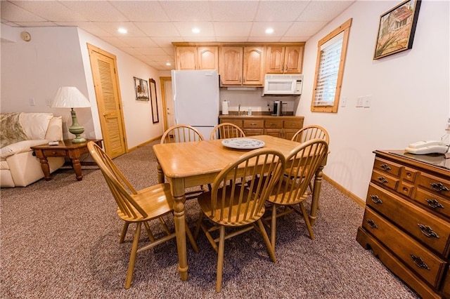 carpeted dining area with sink and a drop ceiling