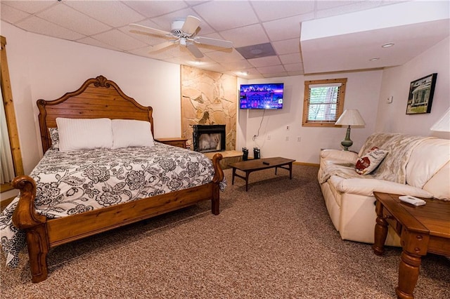 bedroom with ceiling fan, a fireplace, carpet floors, and a drop ceiling