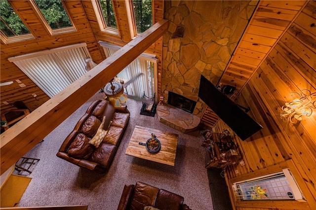 living room featuring a wealth of natural light, wooden ceiling, a fireplace, and wood walls