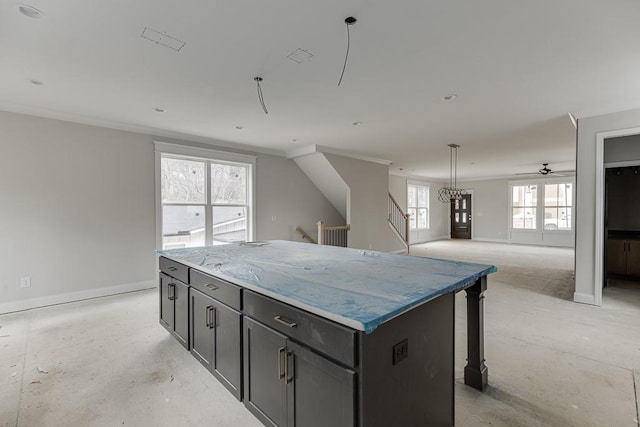 kitchen featuring crown molding, a center island, pendant lighting, and light stone counters