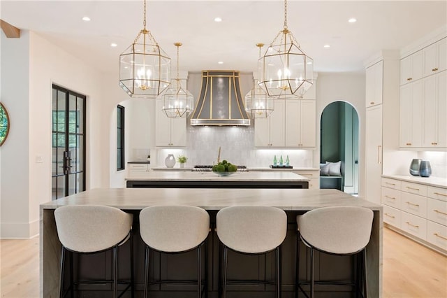 3292 Lenox Pl NE, Atlanta, GA 30324 - kitchen with wall chimney exhaust hood, a chandelier, a center island with sink, backsplash, and recessed lighting