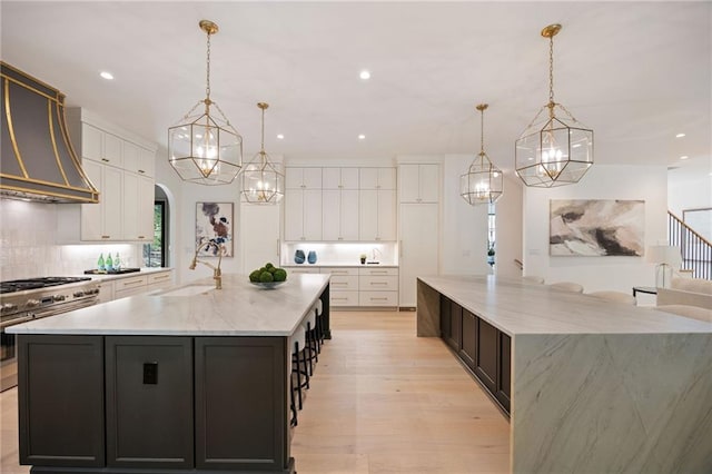 3292 Lenox Pl NE, Atlanta, GA 30324 - kitchen featuring a large island with sink, high end stove, wall chimney range hood, a chandelier, and recessed lighting