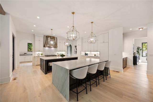 3292 Lenox Pl NE, Atlanta, GA 30324 - kitchen with a large island, custom exhaust hood, recessed lighting, light wood-type flooring, and a chandelier