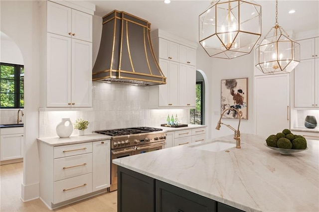 3292 Lenox Pl NE, Atlanta, GA 30324 - kitchen with custom exhaust hood, arched walkways, range with two ovens, a chandelier, and white cabinets