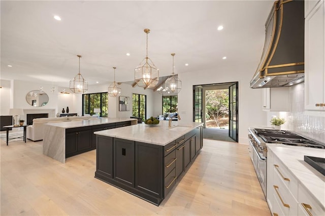 3292 Lenox Pl NE, Atlanta, GA 30324 - kitchen with a spacious island, double oven range, light wood finished floors, recessed lighting, and custom exhaust hood