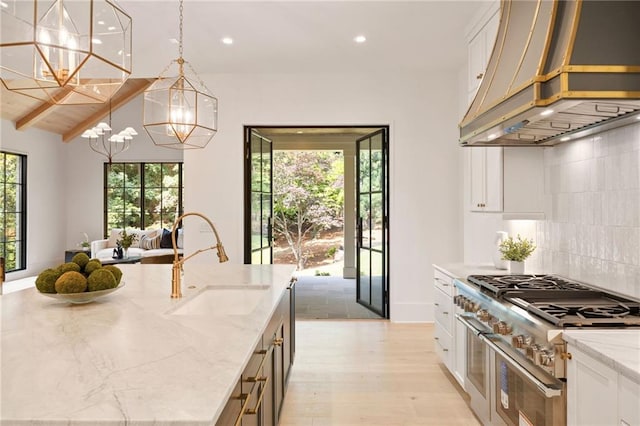 3292 Lenox Pl NE, Atlanta, GA 30324 - kitchen with custom range hood, double oven range, a chandelier, white cabinets, and light stone counters