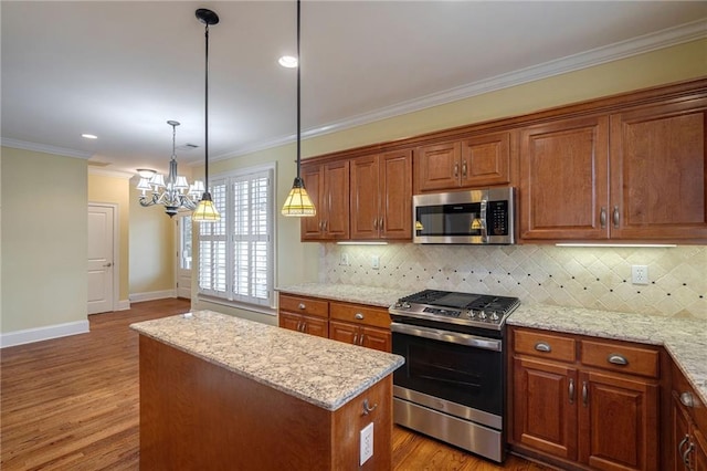 kitchen featuring crown molding, stainless steel appliances, wood finished floors, and a center island