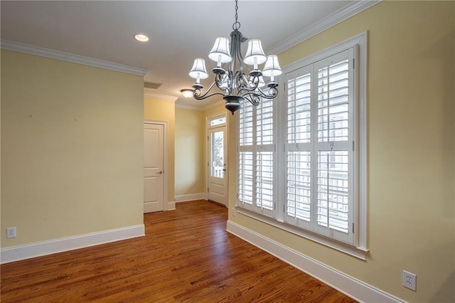 unfurnished dining area featuring visible vents, baseboards, wood finished floors, an inviting chandelier, and crown molding