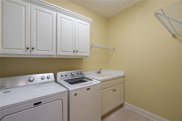 laundry area with light tile patterned floors, cabinet space, a sink, independent washer and dryer, and baseboards