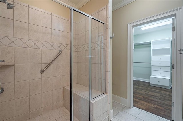 bathroom with a stall shower, ornamental molding, baseboards, tile patterned flooring, and a spacious closet
