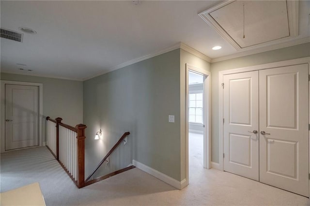 interior space with visible vents, attic access, ornamental molding, light carpet, and an upstairs landing