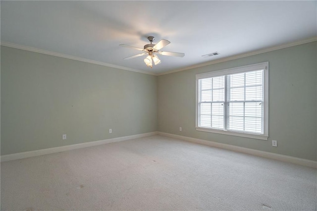 empty room with baseboards, visible vents, crown molding, and light colored carpet