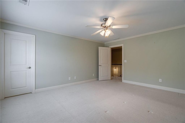 spare room with light carpet, ceiling fan, baseboards, and crown molding