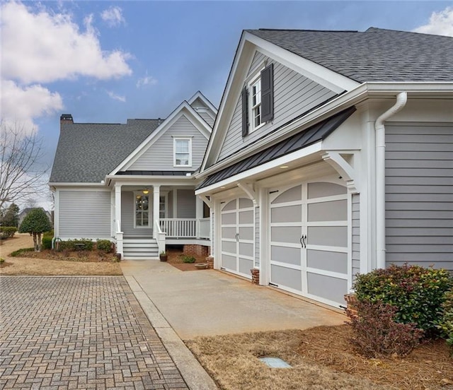 view of front of house featuring covered porch, roof with shingles, driveway, and an attached garage