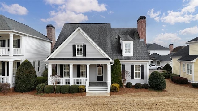 view of front of house featuring a chimney, a porch, a shingled roof, a standing seam roof, and metal roof