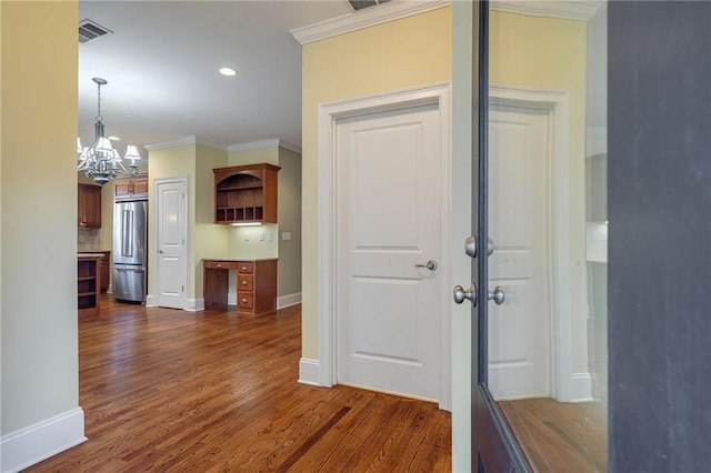 corridor featuring baseboards, dark wood finished floors, visible vents, and crown molding