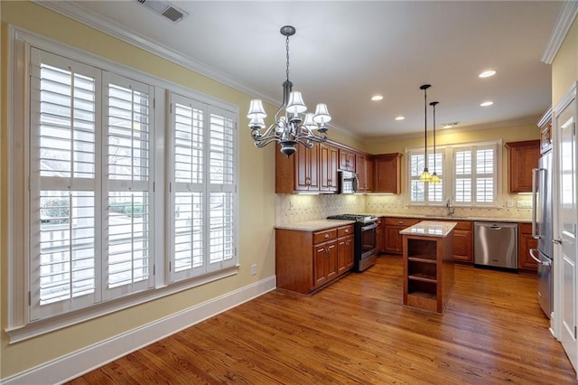 kitchen featuring stainless steel appliances, visible vents, ornamental molding, a sink, and wood finished floors