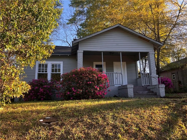 bungalow featuring covered porch and a front yard