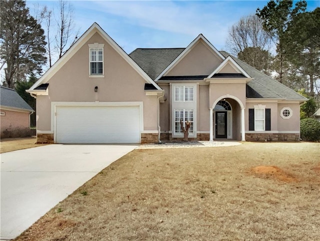 traditional home with concrete driveway, french doors, stone siding, and stucco siding