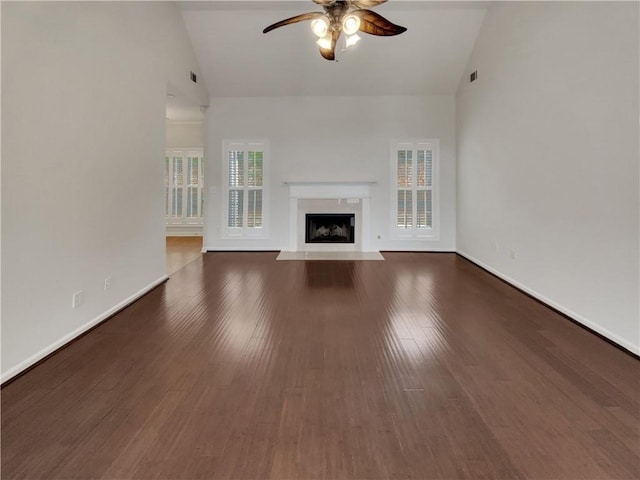 unfurnished living room featuring high vaulted ceiling, a ceiling fan, wood finished floors, a premium fireplace, and baseboards