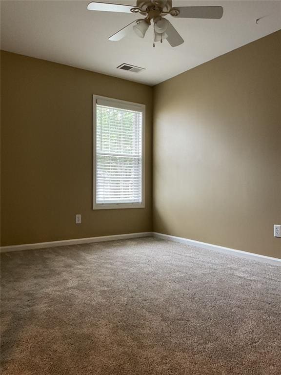 carpeted empty room with baseboards, visible vents, and a ceiling fan