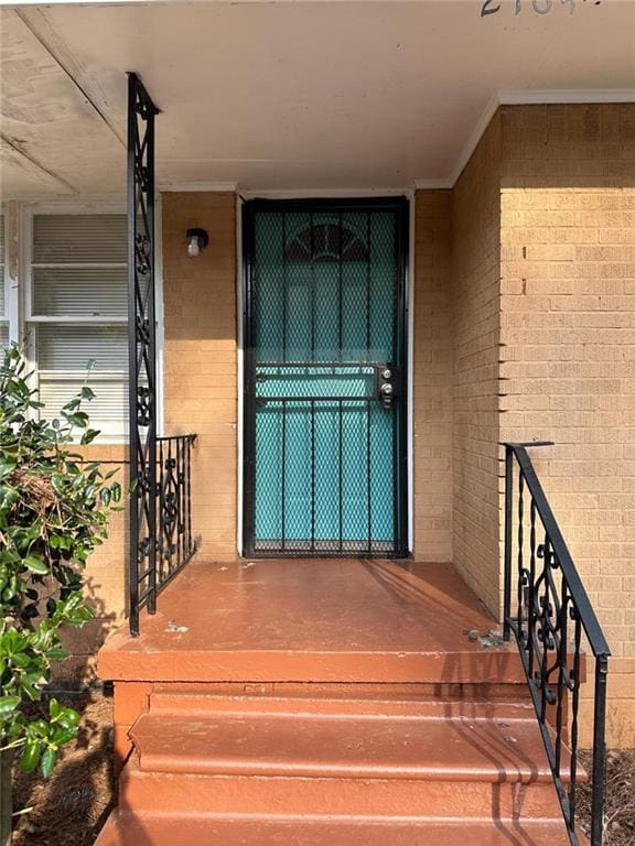 view of exterior entry featuring covered porch and brick siding