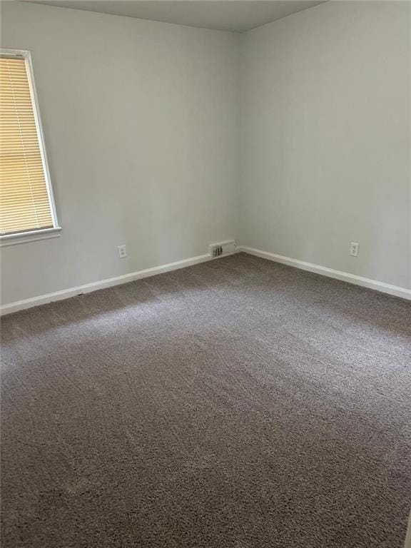 empty room with baseboards, dark colored carpet, and visible vents