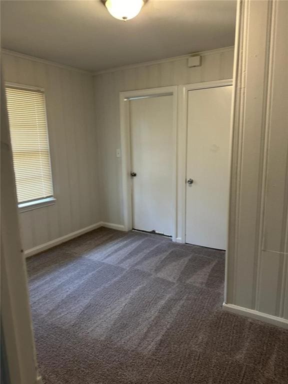 unfurnished bedroom with dark carpet and ornamental molding