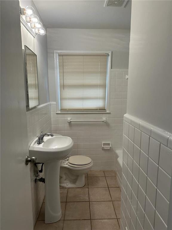 bathroom featuring toilet, radiator, tile patterned floors, tile walls, and a bath