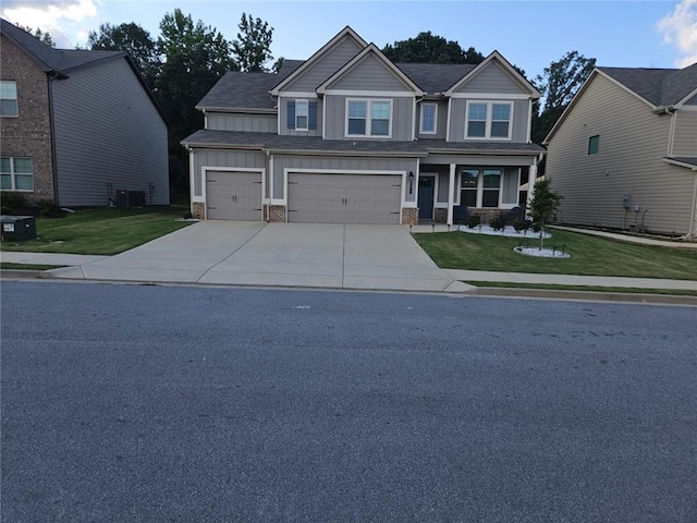 craftsman house with central air condition unit, a garage, and a front lawn