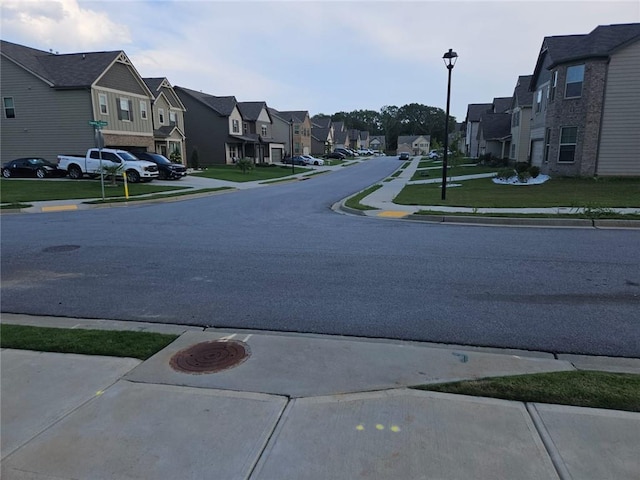 view of road featuring sidewalks, street lights, curbs, and a residential view