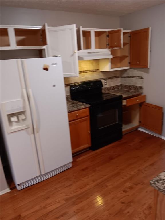 kitchen featuring black electric range oven, white refrigerator with ice dispenser, and dark hardwood / wood-style flooring