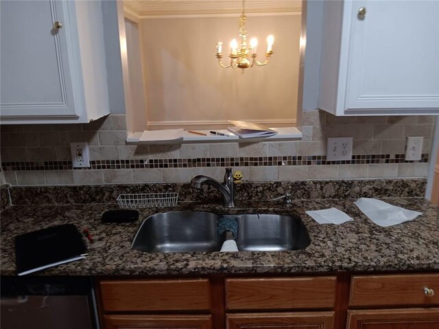 kitchen featuring white cabinetry, sink, dark stone counters, and hanging light fixtures