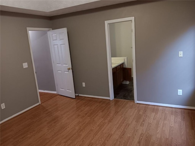 unfurnished bedroom with light hardwood / wood-style flooring and connected bathroom