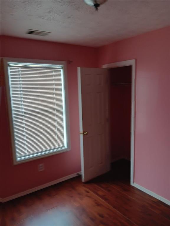 unfurnished bedroom featuring a closet and dark wood-type flooring