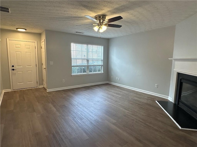 unfurnished living room with ceiling fan, dark hardwood / wood-style flooring, and a textured ceiling