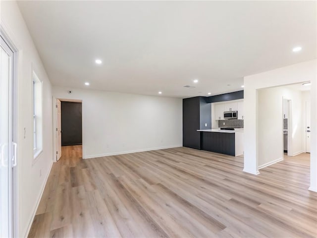 unfurnished living room featuring baseboards, light wood finished floors, and recessed lighting