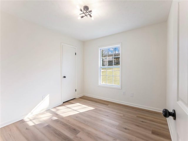 spare room featuring light wood finished floors and baseboards