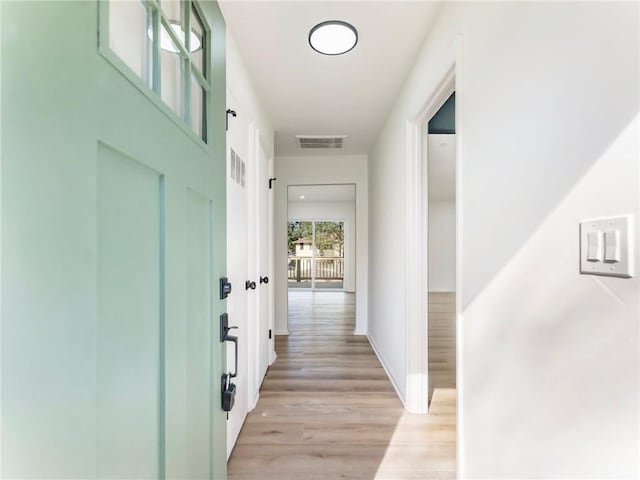 corridor with baseboards, light wood-style floors, and visible vents