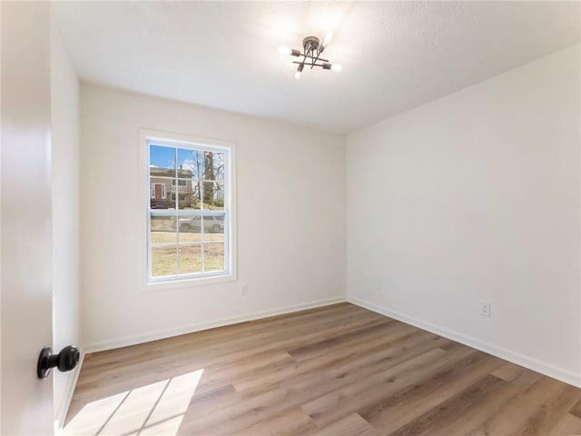 spare room with baseboards and light wood-type flooring